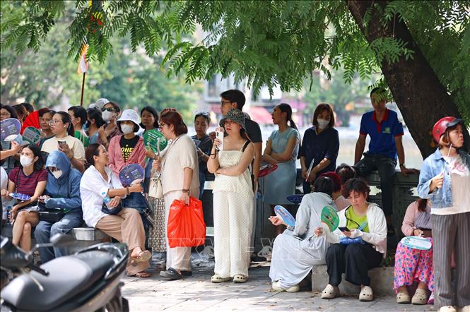 Phụ huynh đợi thí sinh bên ngoài điểm thi Trường THPT Trần Nhân Tông. Ảnh: Thanh Tùng - TTXVN